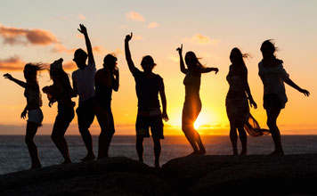 People dancing silhouetted by a beautiful sunset